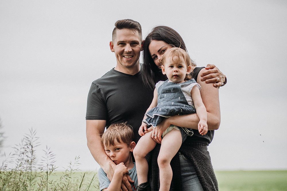 Tyler Badinski with his wife and two children in a prairie field