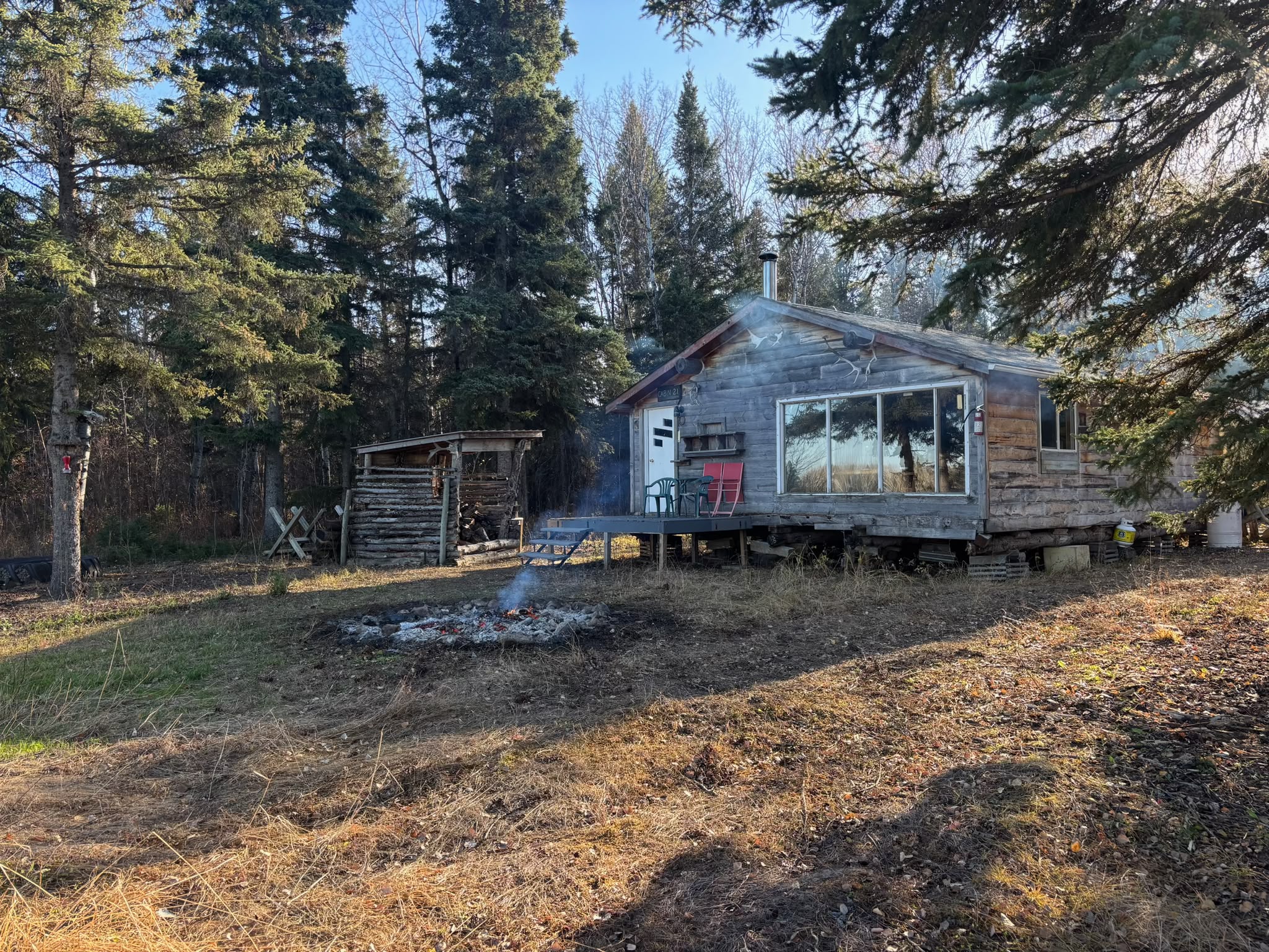 Cabin porch with red chairs and fire pit in autumn forest